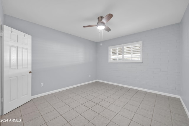 unfurnished room with light tile patterned floors, ceiling fan, and brick wall