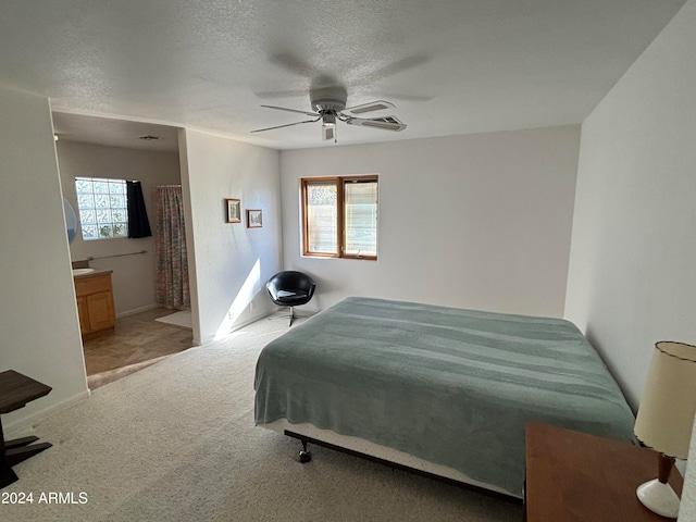 carpeted bedroom featuring a textured ceiling, ceiling fan, ensuite bathroom, and multiple windows