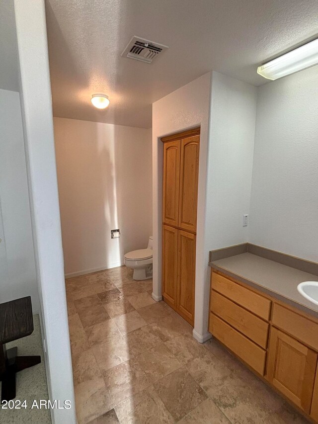 bathroom featuring tile floors, vanity, toilet, and a textured ceiling