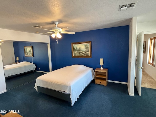 bedroom with ceiling fan, dark carpet, and a textured ceiling