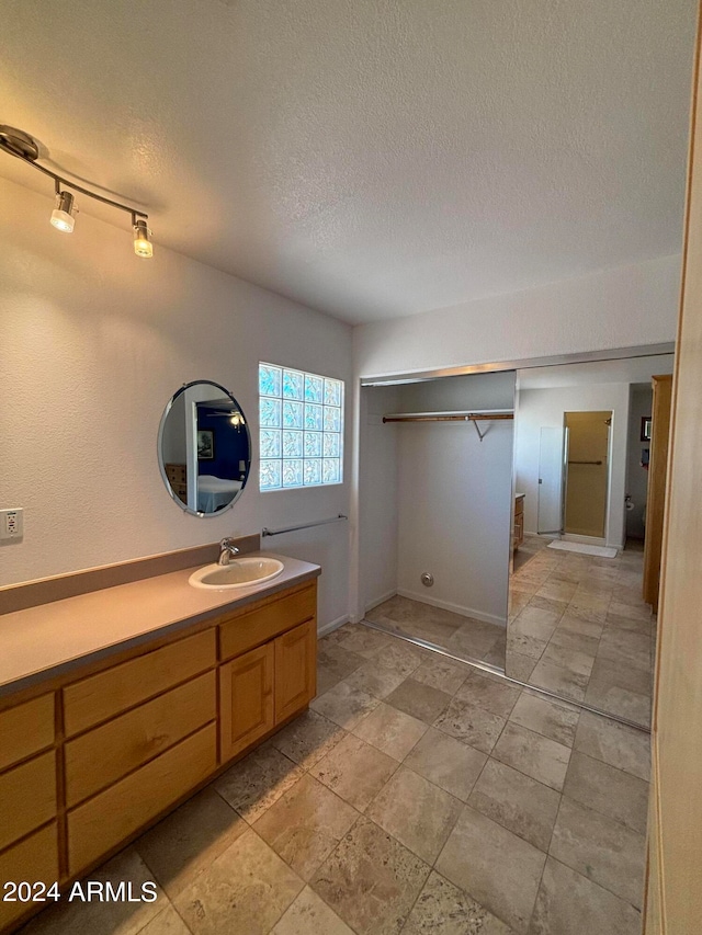 bathroom featuring a textured ceiling, tile floors, vanity, and track lighting