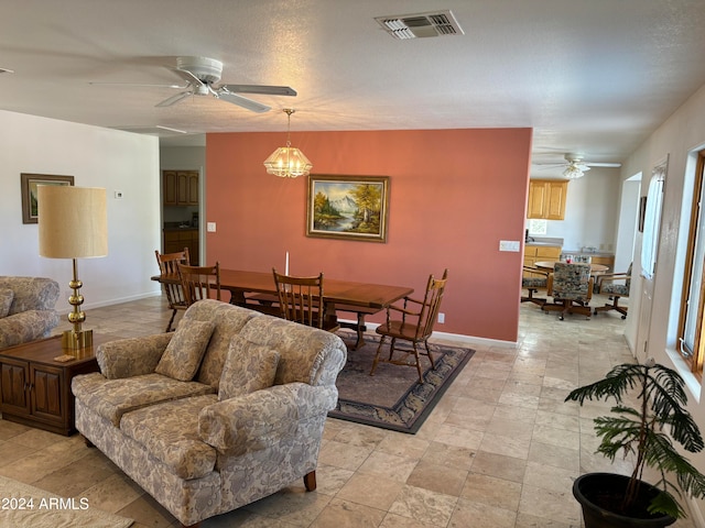 tiled living room featuring ceiling fan with notable chandelier