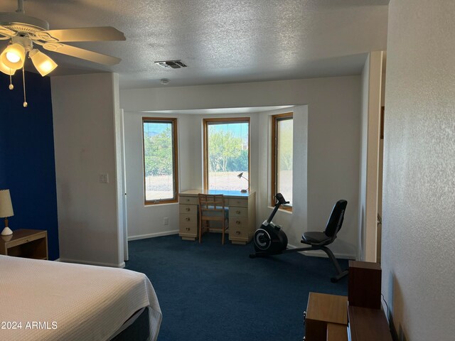 bedroom featuring dark colored carpet, ceiling fan, and a textured ceiling