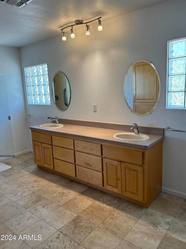 bathroom with tile floors, rail lighting, dual vanity, and a textured ceiling