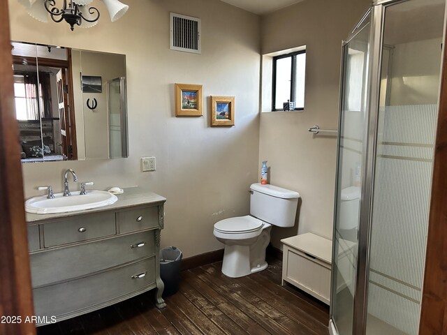 bathroom with wood-type flooring, vanity, toilet, and an enclosed shower