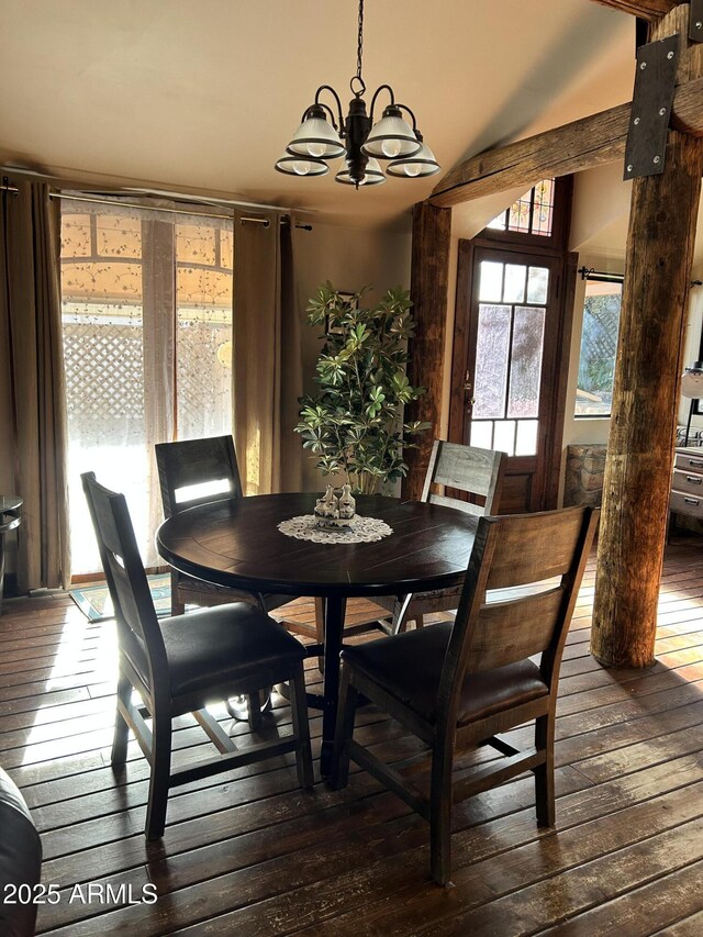 dining space with dark wood-type flooring, lofted ceiling, and an inviting chandelier