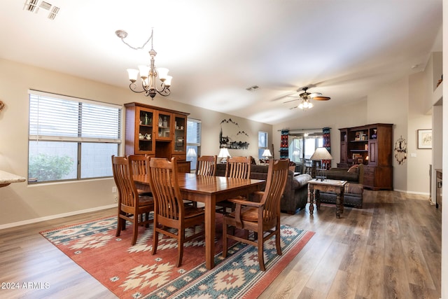 dining room with hardwood / wood-style flooring, ceiling fan with notable chandelier, and vaulted ceiling