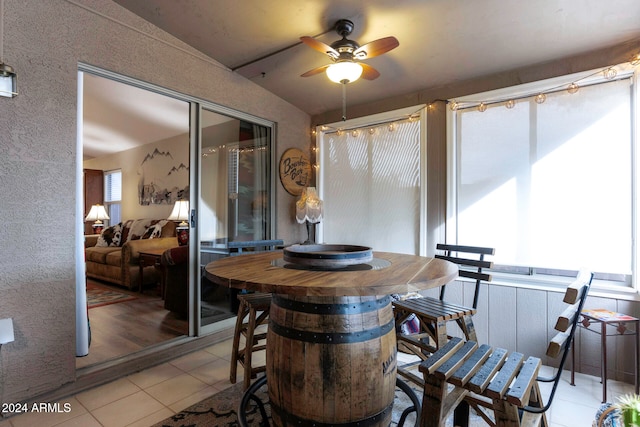 dining room with ceiling fan, light hardwood / wood-style flooring, and vaulted ceiling