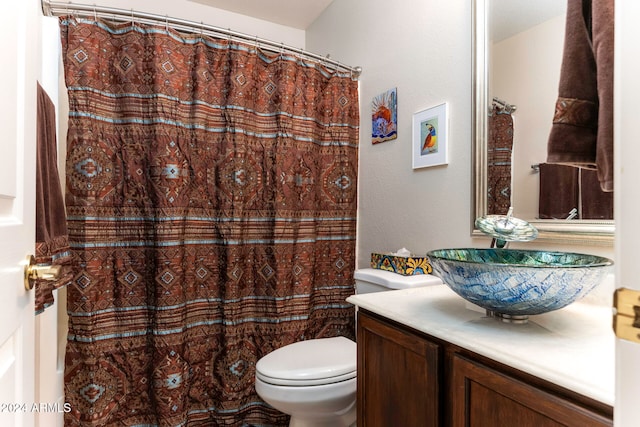 bathroom with curtained shower, vanity, and toilet