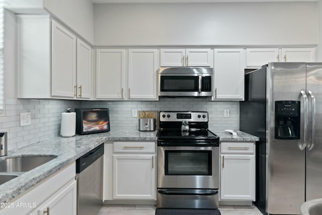 kitchen featuring sink, white cabinetry, light stone counters, appliances with stainless steel finishes, and backsplash