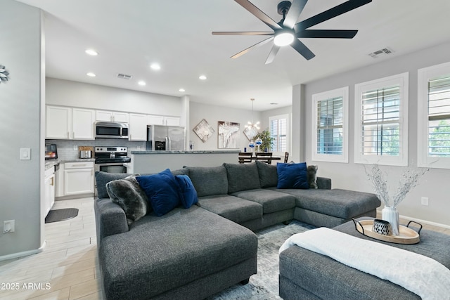 living room featuring ceiling fan with notable chandelier