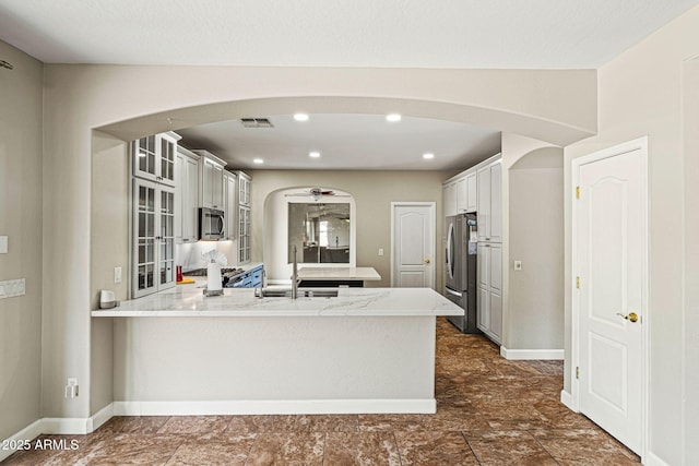 6245 W Maya Dr, Phoenix, AZ 85083 - kitchen with stainless steel appliances, a peninsula, glass insert cabinets, arched walkways, and a sink