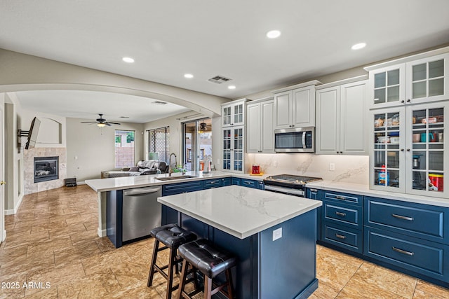 6245 W Maya Dr, Phoenix, AZ 85083 - kitchen featuring stainless steel appliances, a sink, blue cabinetry, arched walkways, and a peninsula