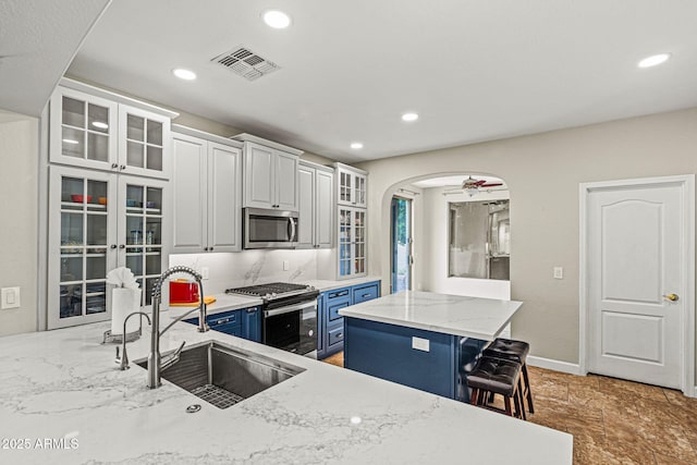 6245 W Maya Dr, Phoenix, AZ 85083 - kitchen with appliances with stainless steel finishes, a sink, blue cabinets, a kitchen breakfast bar, and light stone counters