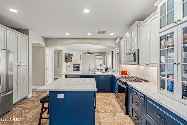 6245 W Maya Dr, Phoenix, AZ 85083 - kitchen with stainless steel appliances, blue cabinets, a ceiling fan, arched walkways, and open floor plan