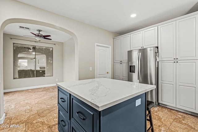6245 W Maya Dr, Phoenix, AZ 85083 - kitchen featuring arched walkways, stainless steel refrigerator with ice dispenser, a kitchen island, white cabinetry, and light stone counters