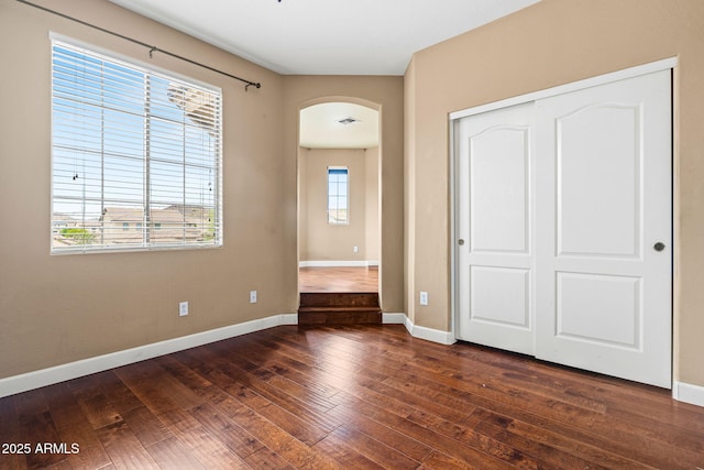 6245 W Maya Dr, Phoenix, AZ 85083 - unfurnished bedroom with arched walkways, dark wood-type flooring, baseboards, and a closet