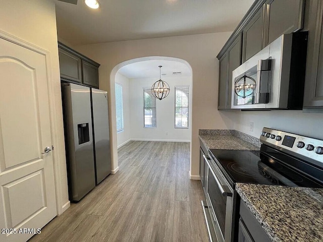 6557 S Classic Way, Gilbert, AZ 85298 - kitchen featuring appliances with stainless steel finishes, arched walkways, a chandelier, light wood-style floors, and dark stone countertops