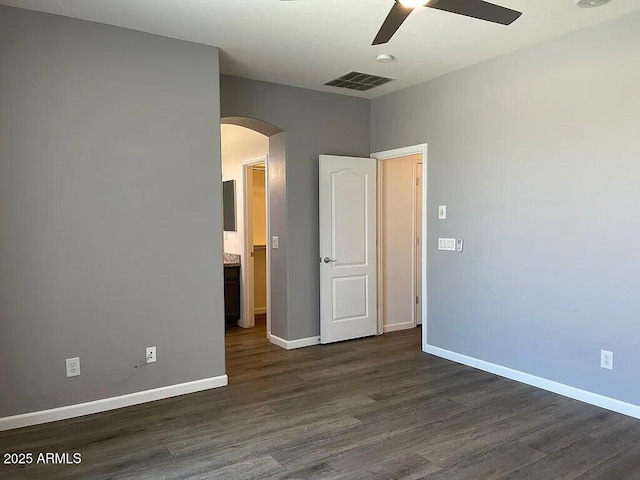6557 S Classic Way, Gilbert, AZ 85298 - unfurnished bedroom featuring arched walkways, dark wood-type flooring, baseboards, and ceiling fan