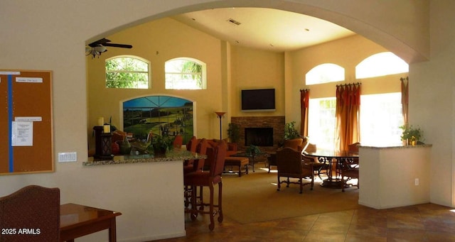 tiled living area featuring visible vents, plenty of natural light, a high ceiling, and a fireplace