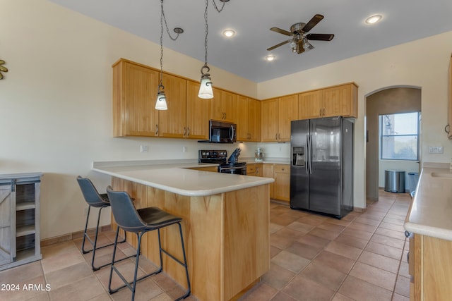 kitchen featuring ceiling fan, pendant lighting, kitchen peninsula, black appliances, and a breakfast bar