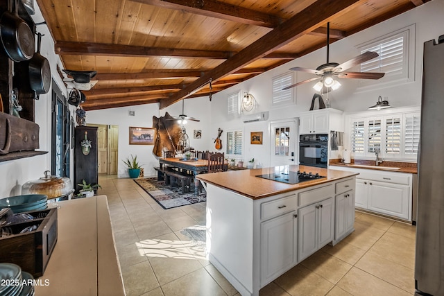 kitchen featuring a center island, light tile patterned floors, white cabinets, and black appliances