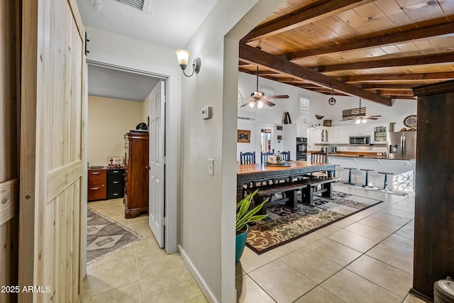 interior space featuring light tile patterned flooring, vaulted ceiling with beams, wood ceiling, ceiling fan, and stainless steel appliances