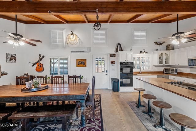 tiled dining area with beam ceiling, ceiling fan, sink, and a wall unit AC