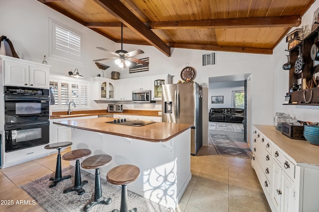 kitchen featuring a kitchen island, sink, white cabinets, a kitchen breakfast bar, and black appliances