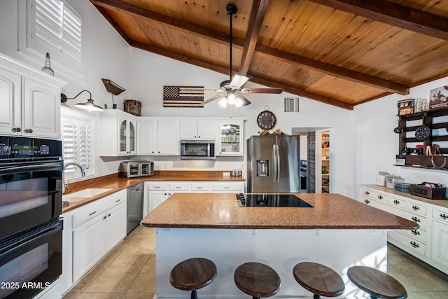 kitchen featuring sink, white cabinetry, a kitchen island, black appliances, and a kitchen bar