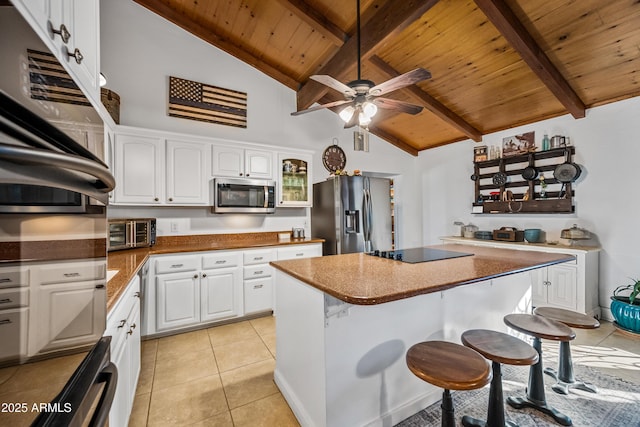 kitchen with appliances with stainless steel finishes, a kitchen breakfast bar, a kitchen island, and white cabinets