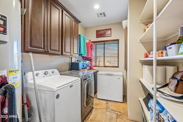 washroom featuring independent washer and dryer, cabinets, and water heater