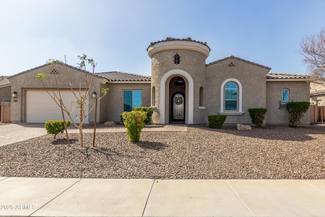 mediterranean / spanish-style house featuring a tile roof, an attached garage, fence, decorative driveway, and stucco siding