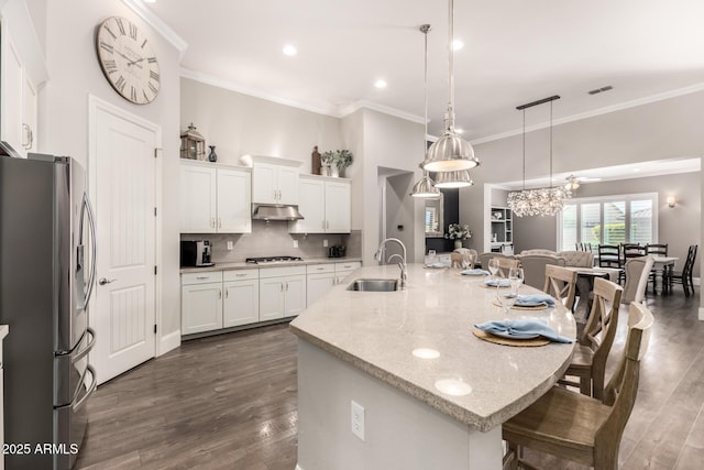 kitchen with stainless steel appliances, a breakfast bar, dark wood-type flooring, a sink, and decorative backsplash