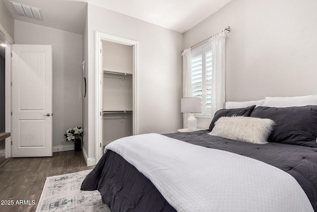 bedroom with a closet, visible vents, baseboards, and wood finished floors