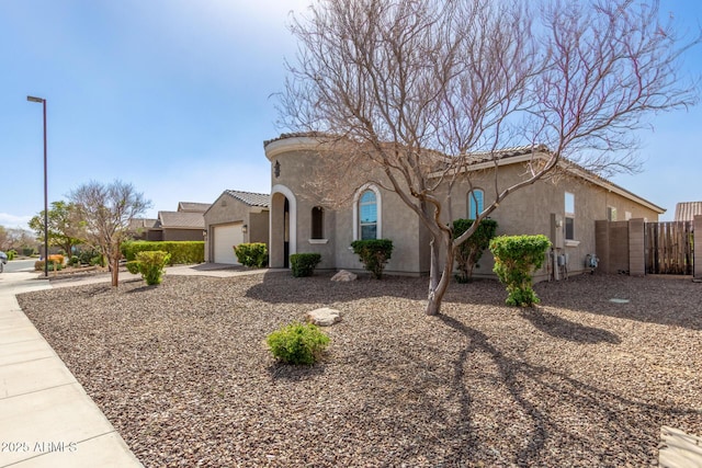 mediterranean / spanish home with a garage, a tile roof, fence, and stucco siding