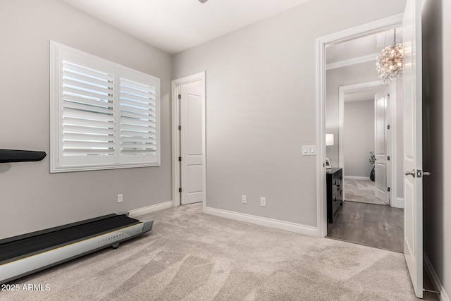 exercise area featuring carpet floors, an inviting chandelier, and baseboards