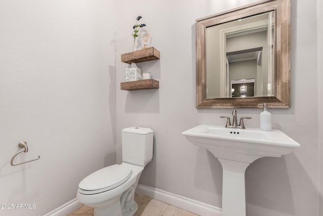 half bathroom featuring tile patterned flooring, toilet, and baseboards