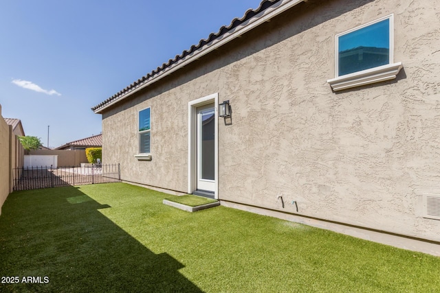 back of property with a tile roof, fence, a lawn, and stucco siding