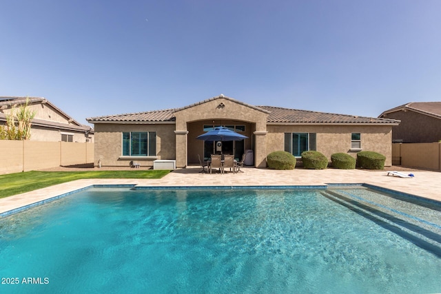 rear view of house featuring a patio, a fenced backyard, a tile roof, and stucco siding