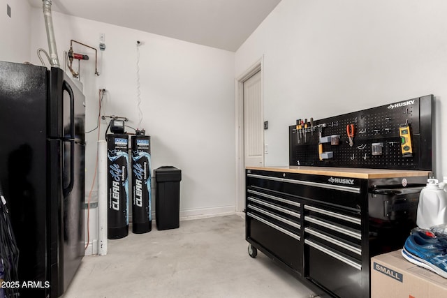 kitchen featuring concrete flooring, freestanding refrigerator, and baseboards