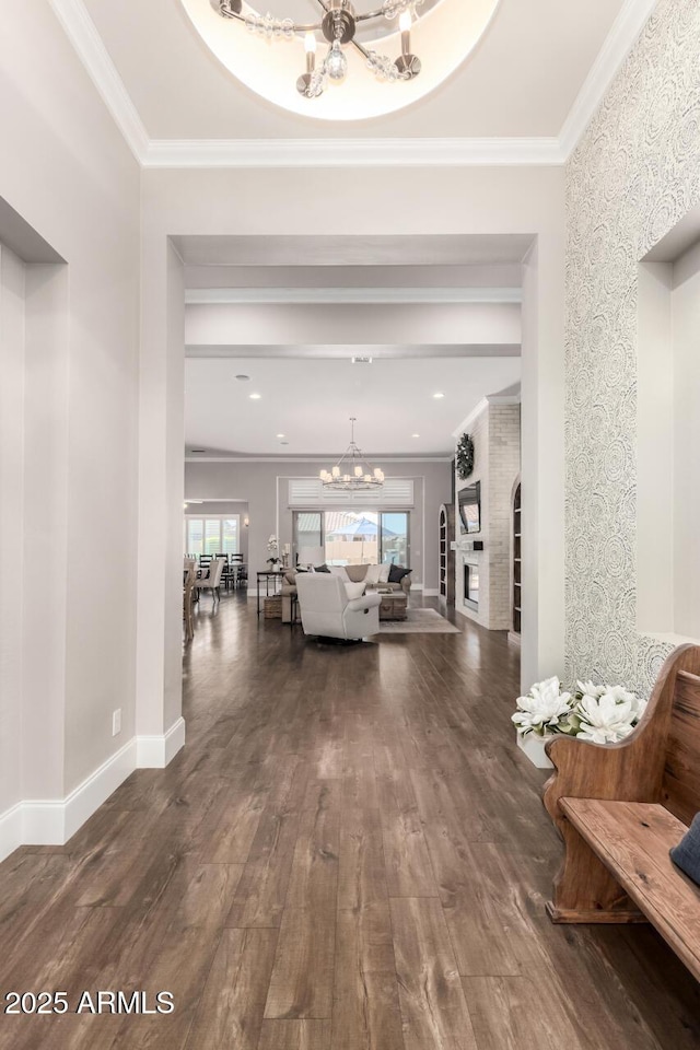 corridor featuring crown molding, dark wood-style flooring, baseboards, and an inviting chandelier