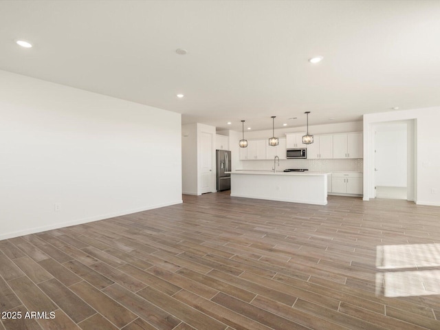 unfurnished living room with wood-type flooring and sink