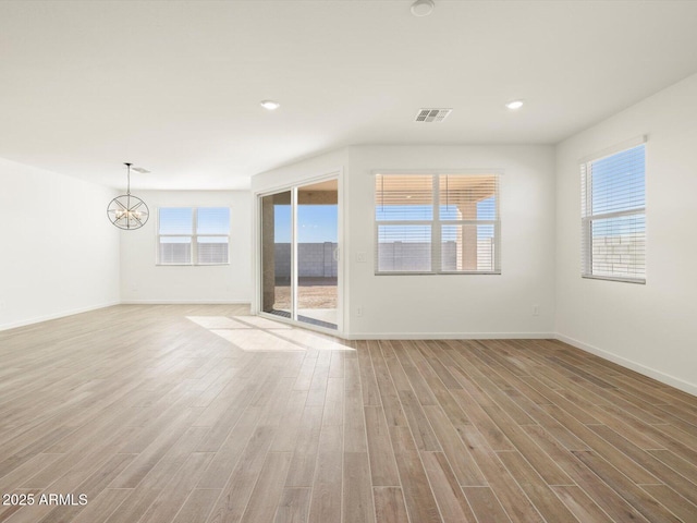 empty room with light hardwood / wood-style flooring and a chandelier