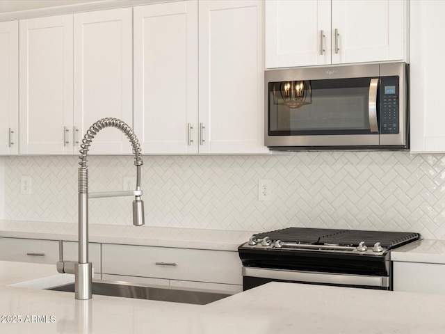 kitchen featuring stainless steel appliances, white cabinets, decorative backsplash, and sink