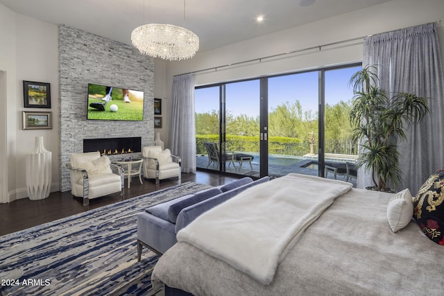 bedroom with a stone fireplace, access to outside, a chandelier, and dark wood-type flooring