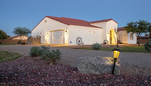 mediterranean / spanish-style house with driveway, a garage, a tile roof, fence, and stucco siding