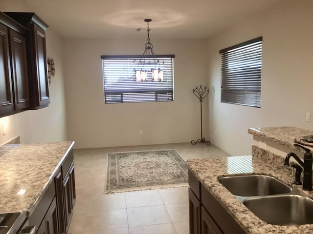 kitchen with dark brown cabinets, a sink, a wealth of natural light, and pendant lighting