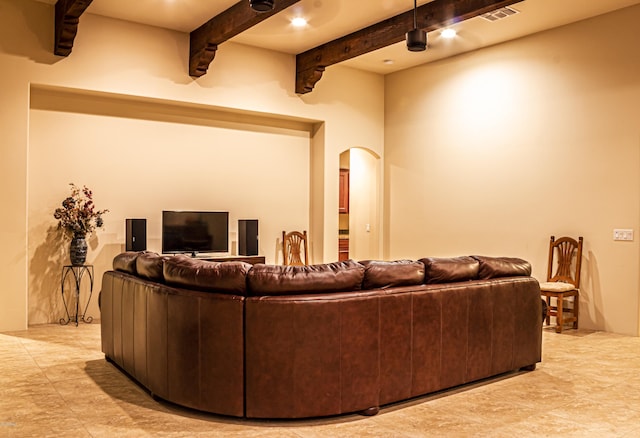 living room featuring arched walkways, beamed ceiling, and visible vents