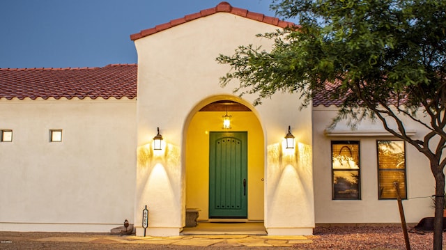 entrance to property with a tile roof and stucco siding